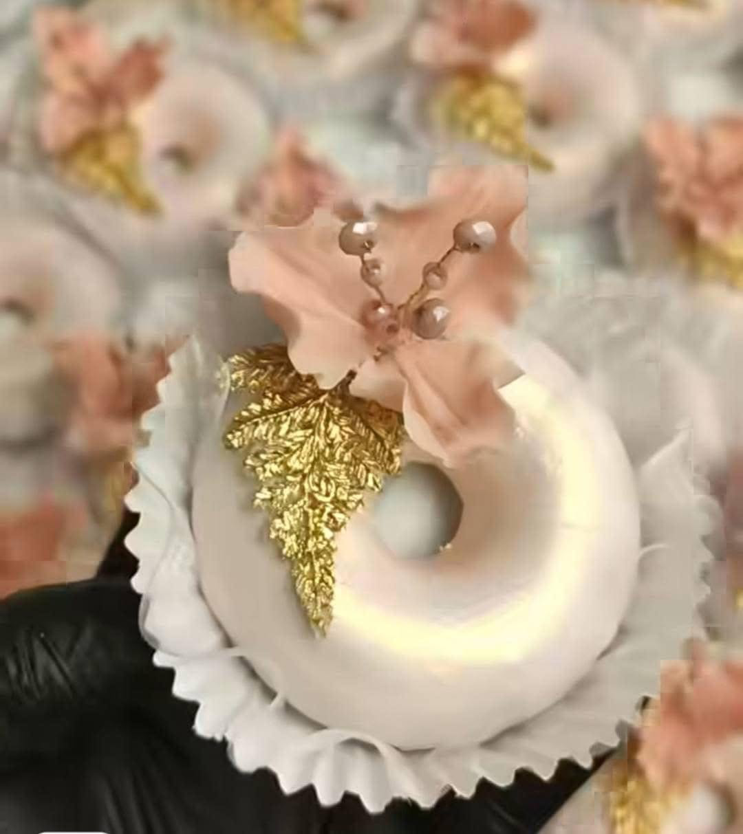 Gâteau ivoire orné d'une feuille dorée et d'une fleur rose